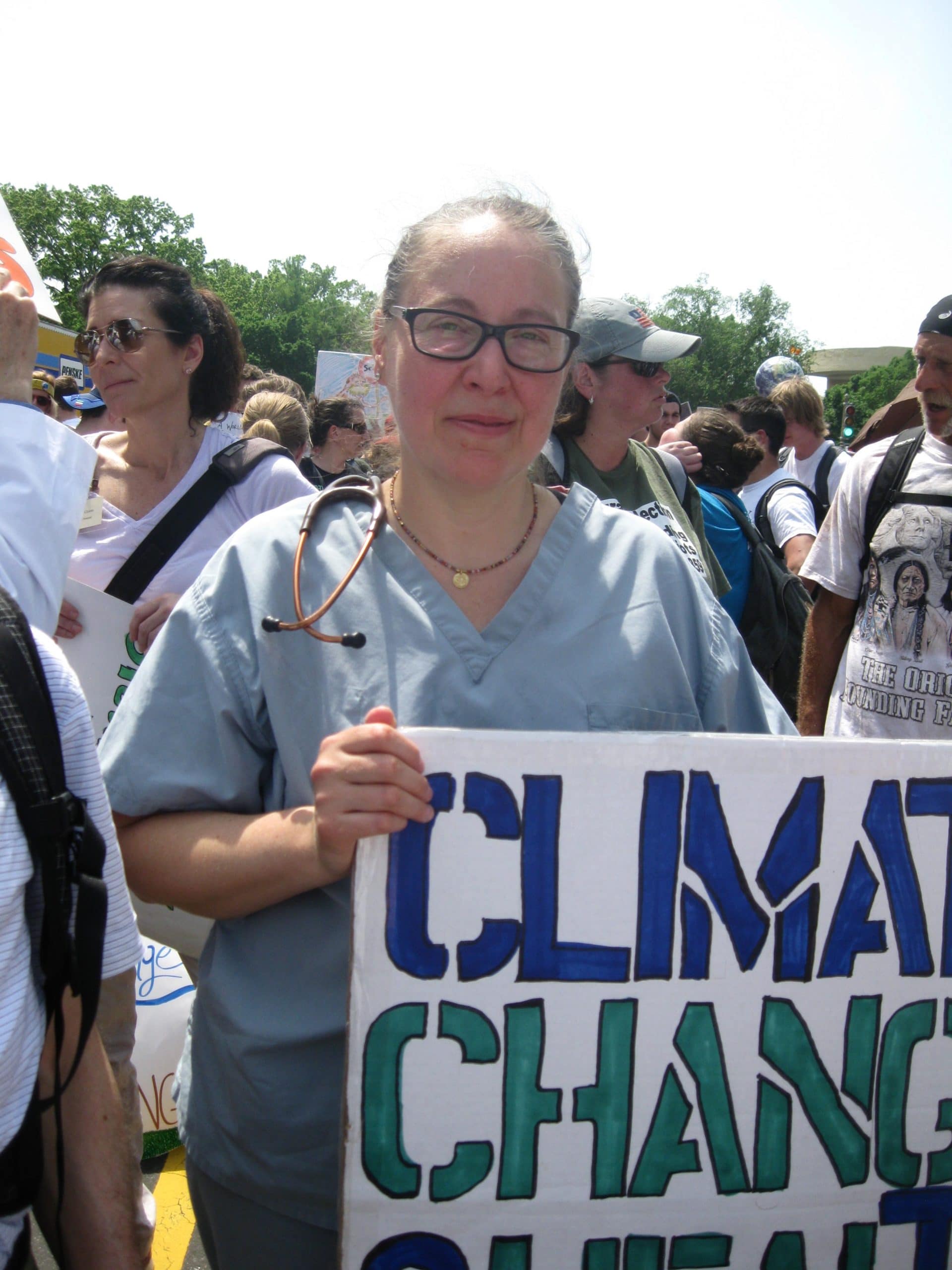 PSR doctor in scrubs holding "Climate Change" sign