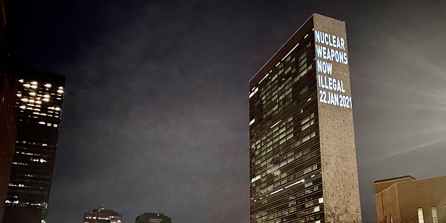 UN Headquarters with light projection reading "Nuclear weapons are now illegal"